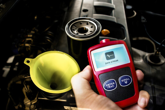 Car engine maintenance with oil filter, funnel, and OBD2 diagnostic scanner showing data stream for vehicle checkup