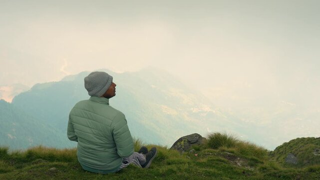 Person Meditating on Grassy Hill Overlooking Misty Mountain Range Rudranath Temple Trek, Uttarakhand, India