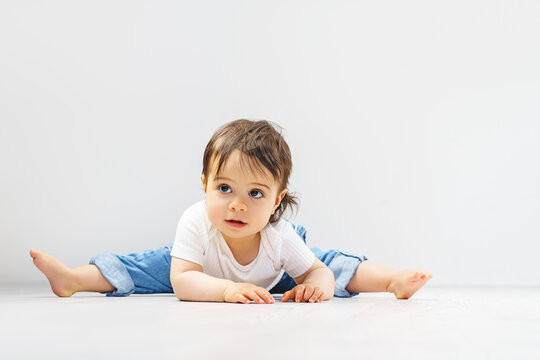A sweet little girl is doing the splits on the floor. Healthy development in children. Children's gymnastics.