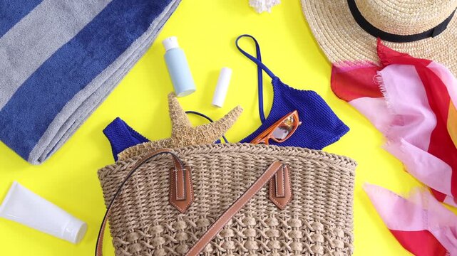 Bag with beach accessories on yellow background, flat lay