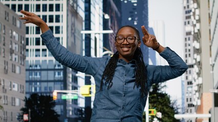 Black woman performing stylish street dance movements on city street, Young adult having fun with vibrant dancing activity on sidewalk in the city center.