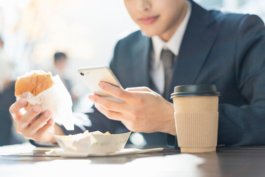 ハンバーガーとスマートフォンを持つ手元
