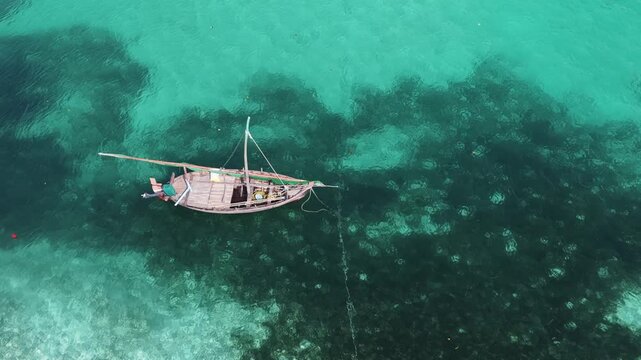 Aerial view of a traditional wooden dhoni boat floating in clear turquoise lagoon waters in Vaikaradhoo, Haa Dhaalu Atoll, Maldives.