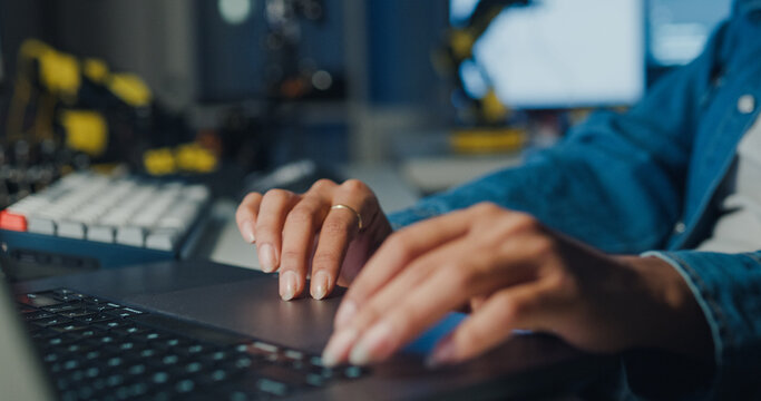 Close-up young Black female programmer coding AI software on multiple screens in night office. Network security, cybersecurity, machine learning, working late, overtime, robotics automation concept.