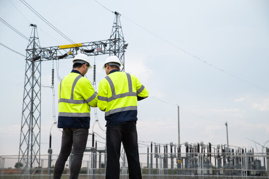 Engineers Reviewing Technical Reports at Modern Electrical Power Grid Installation Site