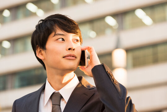 銀杏並木で電話する20代男性ビジネスマン