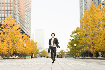 高層ビル街を走る20代男性ビジネスマン © One