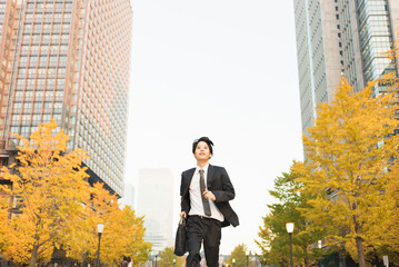 高層ビル街を走る20代男性ビジネスマン © One