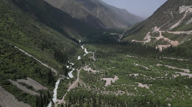 Aerial view of the lush Ala Archa National Park valley with a winding river, dense pine forests, and steep mountain slopes in Bishkek, Bishkek City, Kyrgyzstan.