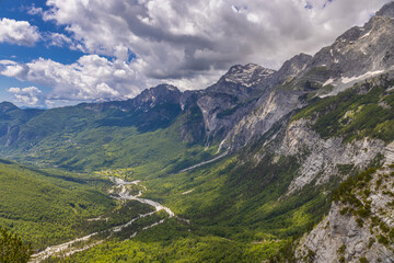 Fototapeta premium Mountain landscape in the Albanian Alps near Theth, Albania. Theth Valbona valley trek Peaks of the Balkans scenic way. Rugged peaks rise above forested valleys and alpine meadows