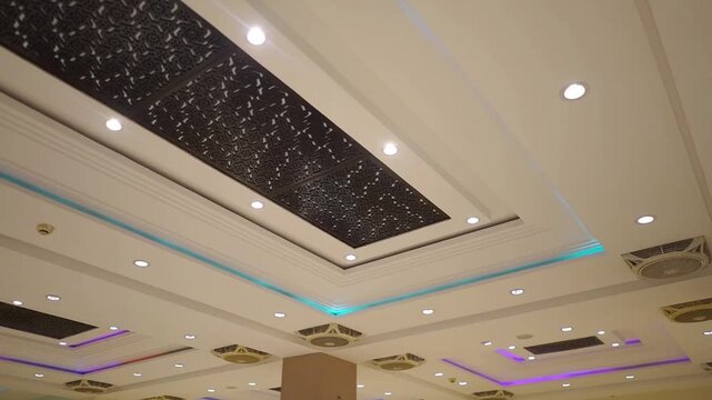 Video footage of an elegant wedding hall ceiling featuring decorative patterns, recessed lighting, themes related to event venues, banquet halls, luxury interiors, celebrations, hospitality, 