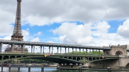 Fototapeta premium Bir-Hakeim Bridge and Eiffel Tower Under Cloudy Parisian Sky