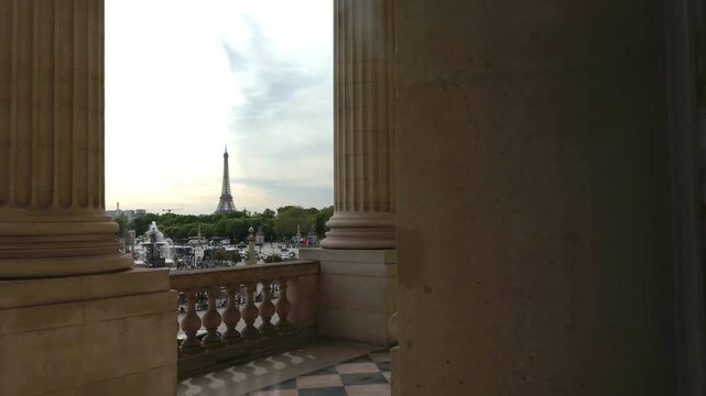 Famous Eiffel Tower landmark viewed from between the classical columns of a building on the Place de la Concorde, a beautiful and historic public square in the heart of Paris, France