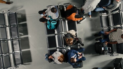 Holding travel documents, top down view and passengers crowd in busy airport terminal, Looking at plane tickets, long flight layover and high angle shot of group of people. © DC Studio