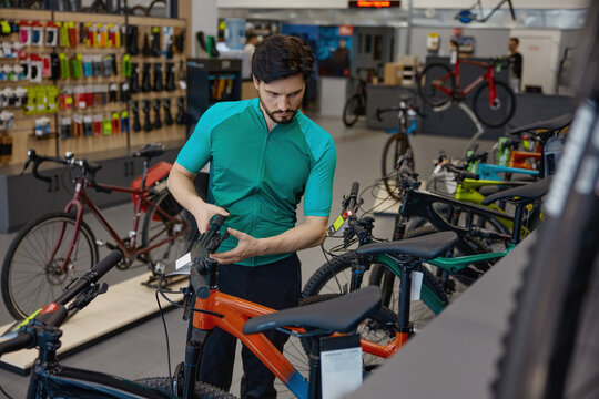 Product consultant prepares for test ride amidst neatly arranged bicycles and retail environment