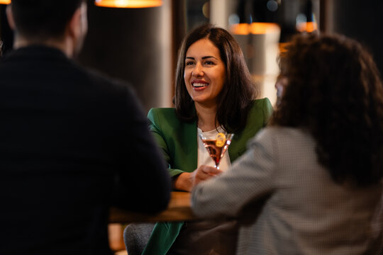 Woman socializing with friends enjoying cocktails in bar