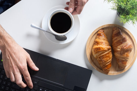 Remote Work Breakfast with Coffee and Croissants on Home Office Desk. Top view
