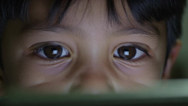Screen glowing, Asian child watching content on tablet at dim room, with square catchlights