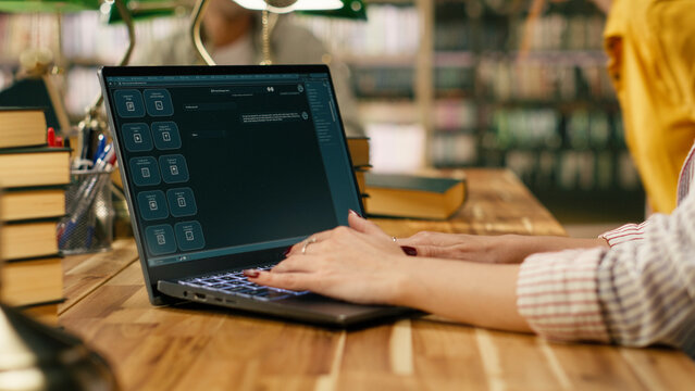 Student uses laptop with AI chatbot interface at library table, modern learning tool and virtual assistant with classmates studying nearby.