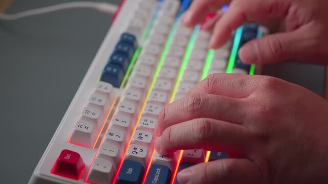 Close up of male hands typing on a backlit mechanical keyboard
