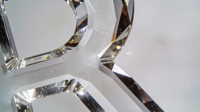 Catching point light, faceted crystal letter throwing flares on gray table, showing dust scratches