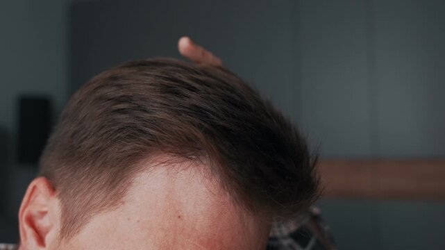 Close-up of men's hair on the head, hairstyles. The hand runs through the hair, showing the styling details. Beautiful styling of men's hairstyles