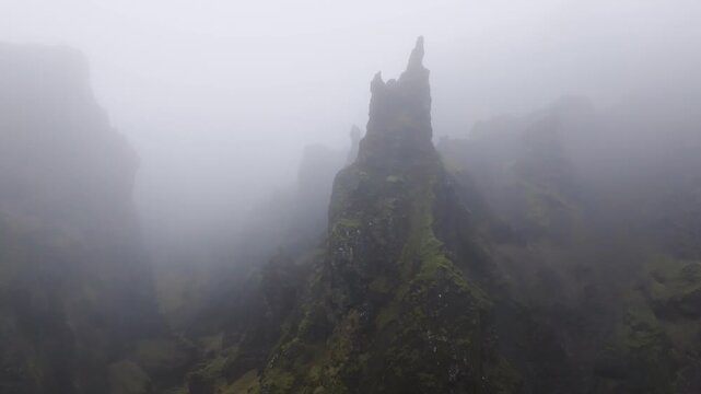 Aerial view of jagged mossy rock pinnacles rising through thick mist in Iceland.