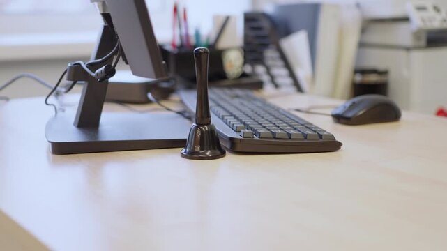 Microphone standing near computer monitor and keyboard. Blurry office background reveals printer machine in addition to document organizers