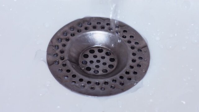 Clear Water Flowing into a Stainless Steel Kitchen Sink Drain Strainer