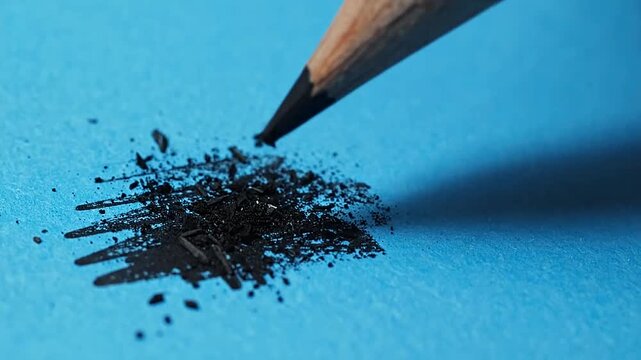 Macro shot of a broken pencil tip on blue paper