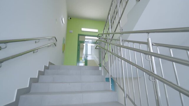 Shiny steel handrails mounted on walls along school steps. Professional design emphasizes functionality of contemporary infrastructure