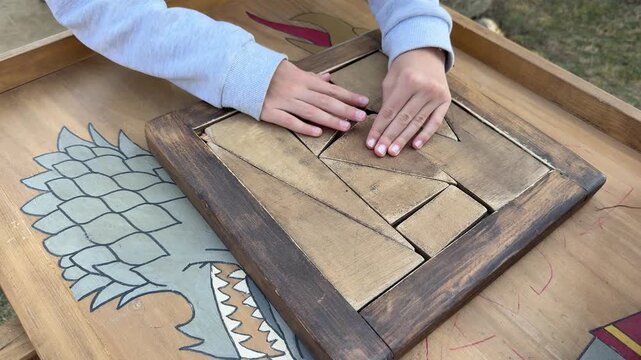 Hands solving wooden puzzle game, tabletop brain teaser close up