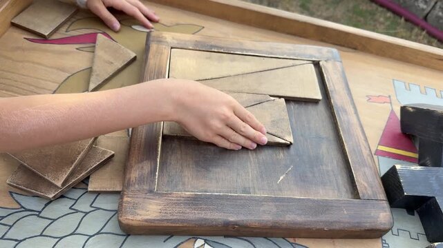 Hands solving wooden geometric puzzle, tabletop brain teaser close up. 