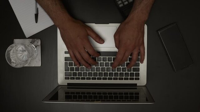 Top View of Accountant Typing on Laptop with Calculator and Notepad on Desk