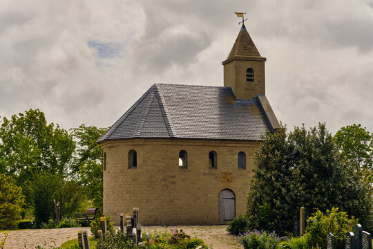 Stroe, Netherlands - 20 May 2026: View of the Heathen Chapel, a small stone structure with a pointed tower, situated in a graveyard under a cloudy sky in Wieringen.