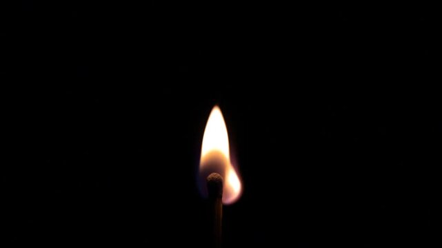 Bright flame dances against deep black background. Matchstick ignites with crisp, warm glow. Simple light reveals quiet intensity. Ideal for themes of ignition, discovery, or transformation
