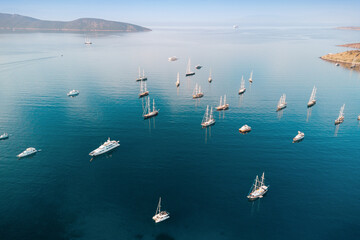 Obraz premium Aerial view of luxury yachts, sailboats, and gulets in a serene bay, capturing summer travel and relaxing holidays in blue waters