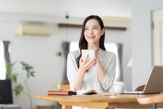 リビングで家計簿をつけるミドルの女性