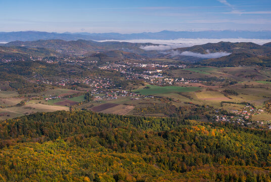 Aerial view of the landscape around Sitno mountain, featuring dense autumn forests, rolling hills, and the village of Ilija, Banska Bystrica Regio, Slovakia.