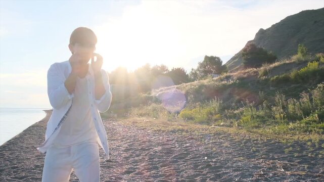 Teenage boxer shadowboxing on a seashore at sunset, throwing jabs in slow motion. Boxing training and fitness workout concept with a young athlete practicing punches by the sea.