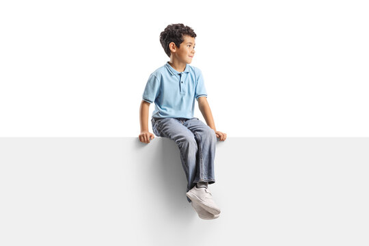 Young boy sitting on a white panel and looking away to the side