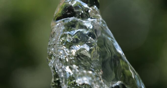 Water jet. Top of water fountain. Flow of pure spring water on a green natural background.