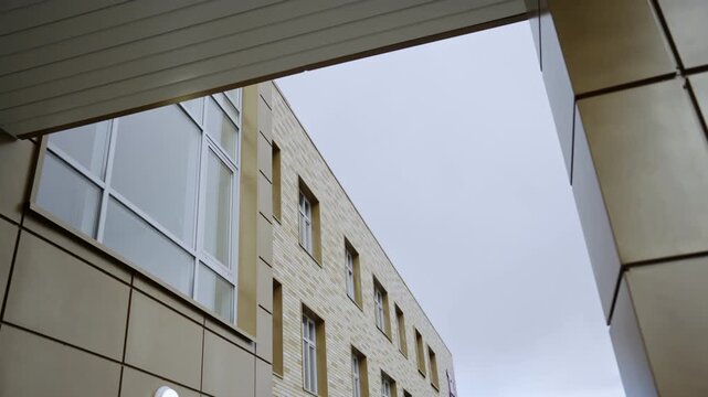 Building facade with beige panels and large windows under grey sky. Modern architectural style creates professional business atmosphere