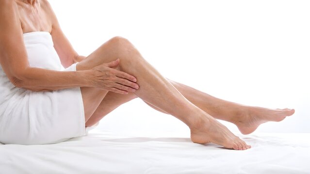 Mature woman's legs with gentle touch during self-care illuminated by soft studio light conveying wellness and aging gracefully