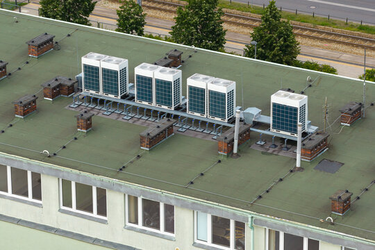 Aerial view of modern HVAC air conditioning units installed on a green flat rooftop of a building in Warsaw, Masovian Voivodeship, Poland.