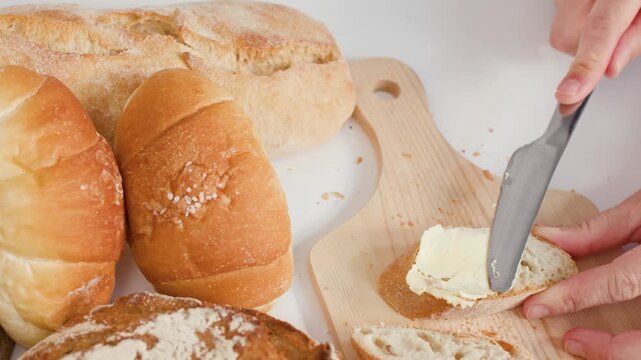 Close Up of Hands Spreading Butter on Sliced Artisan Baguette