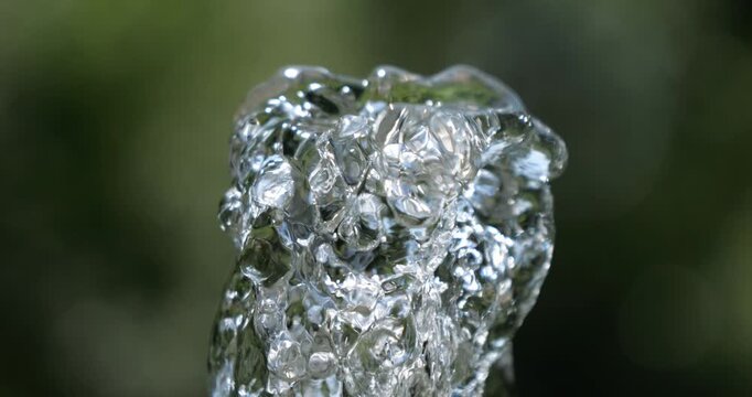 Water jet. Top of water fountain. Flow of pure spring water on a green natural background.