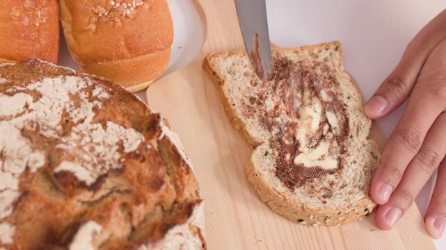 Spreading Peanut Butter on Multigrain Bread Slice with Assorted Loaves