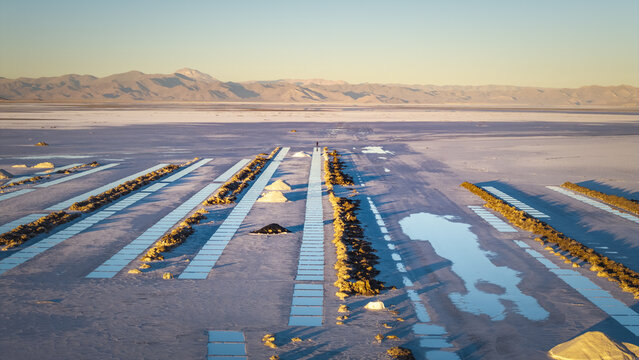 Aerial view of Salinas Grandes salt flats featuring geometric extraction pools and salt mounds under a clear sky in La Poma Department, Salta Province, Argentina.