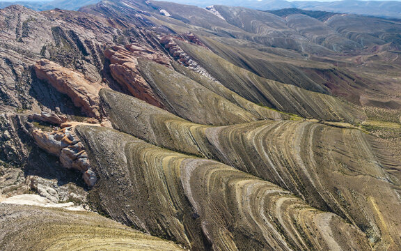 Aerial view of the Gigantes Dormidos geological formation featuring dramatic folded rock strata, rugged mountain ridges, and arid desert terrain in Tres Cruces, Jujuy Province, Argentina.